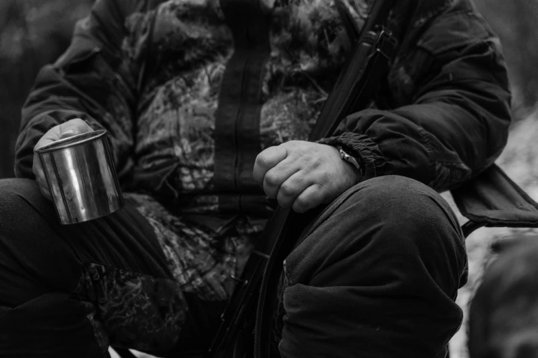 a man sits with a backpack and drink