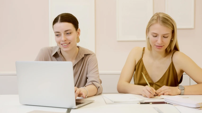 two girls are looking at a laptop screen