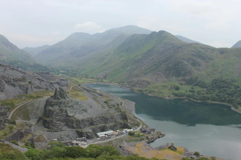 a lake surrounded by mountains and rocks under a gray sky