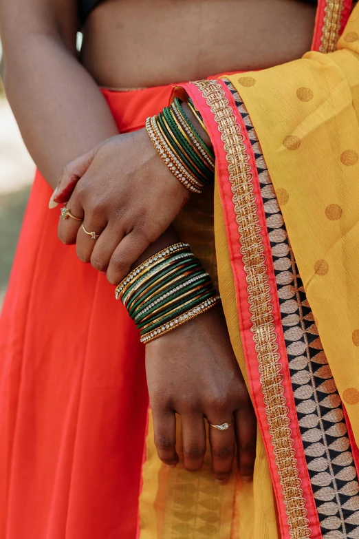 a woman in an orange and yellow outfit holding her hands in a knot