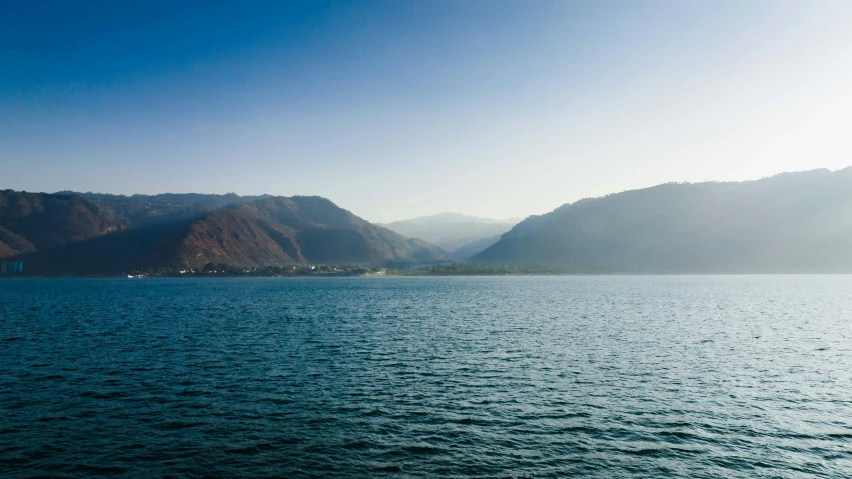 a lake is surrounded by mountains with blue sky