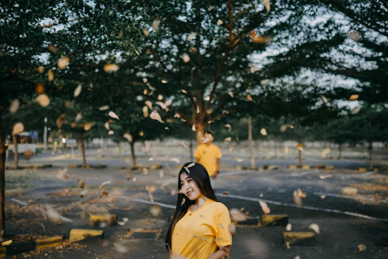 a woman in a yellow shirt is standing outdoors