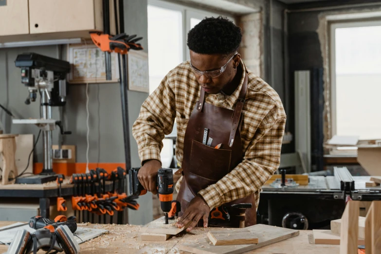 a man is in his work shop using a drill bit