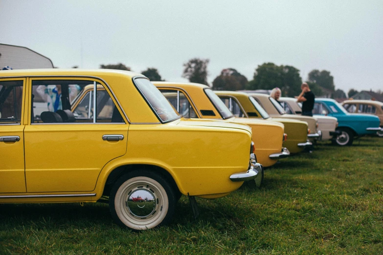 the yellow car is parked along with blue and white cars