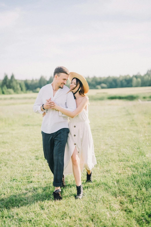 a man in a hat and woman in a white dress standing in a field