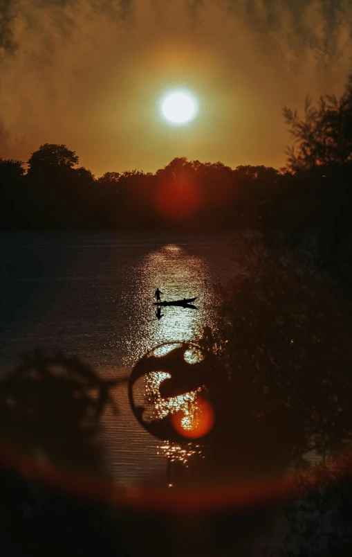 the sun is setting over a lake with some trees