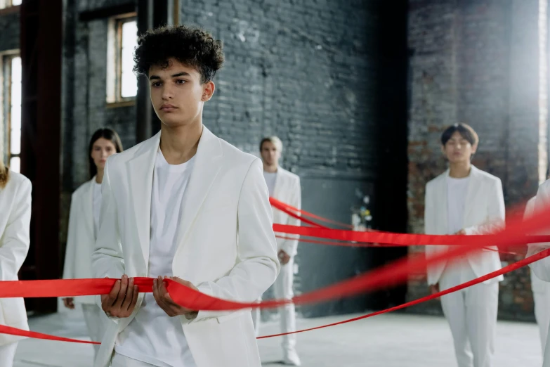 people standing in a building, all wearing white and red with one man in the middle wearing a suit