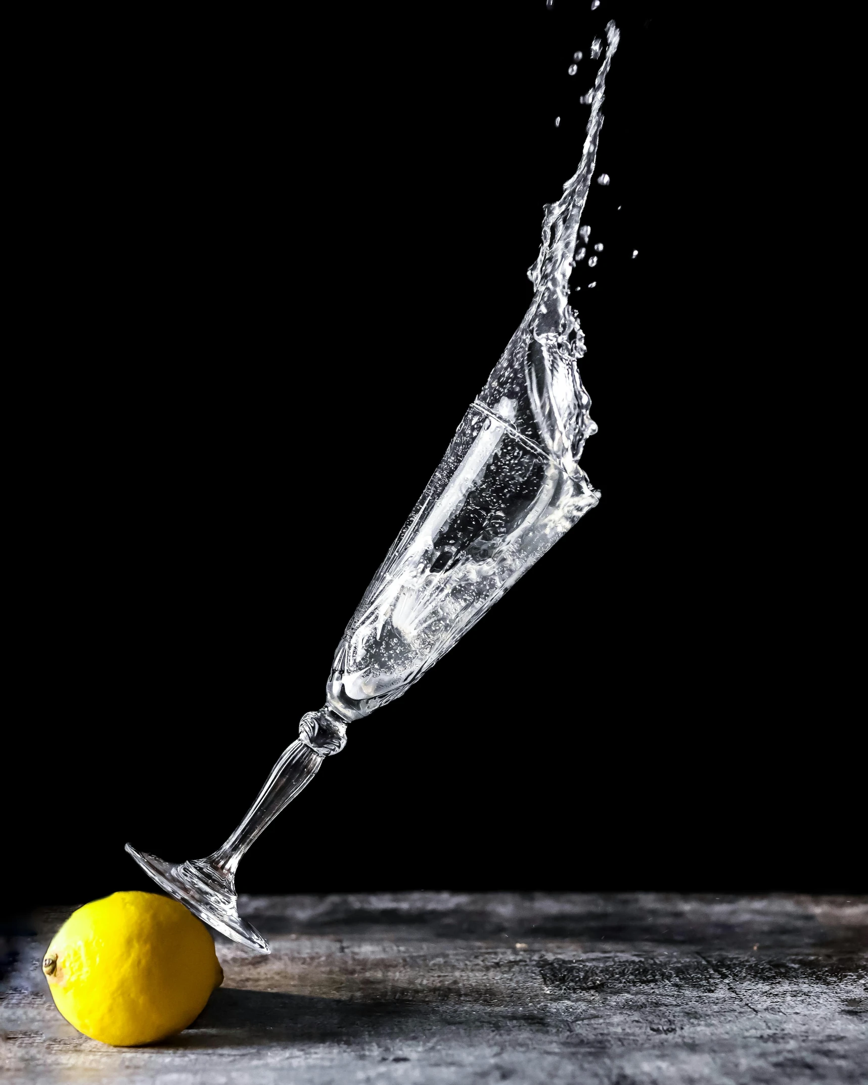 lemon being squeezed into a glass with water