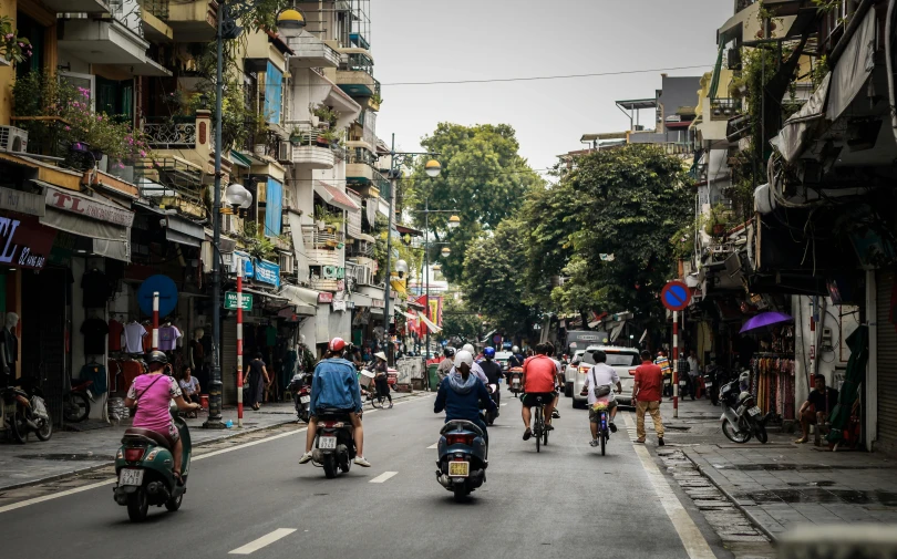 several motorcycles ride down the street surrounded by buildings