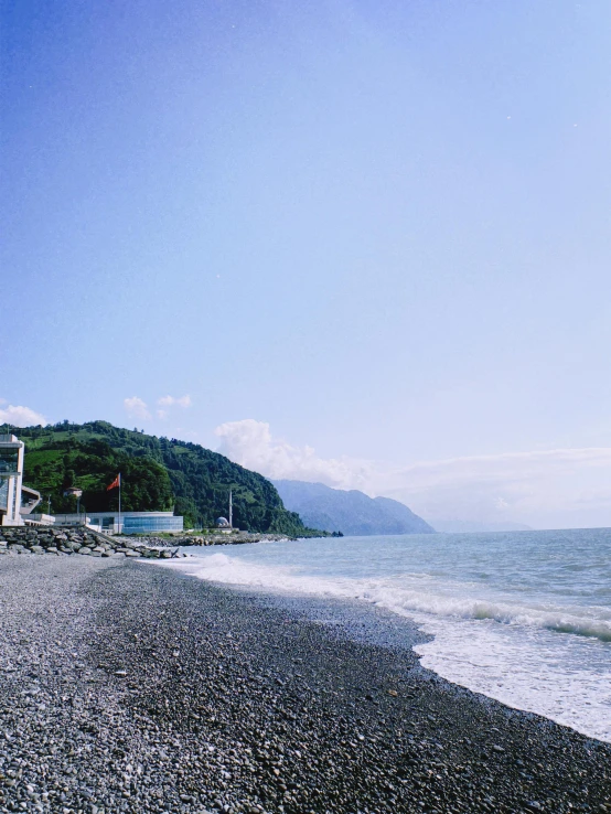 a rock beach on a clear day with waves crashing in the water