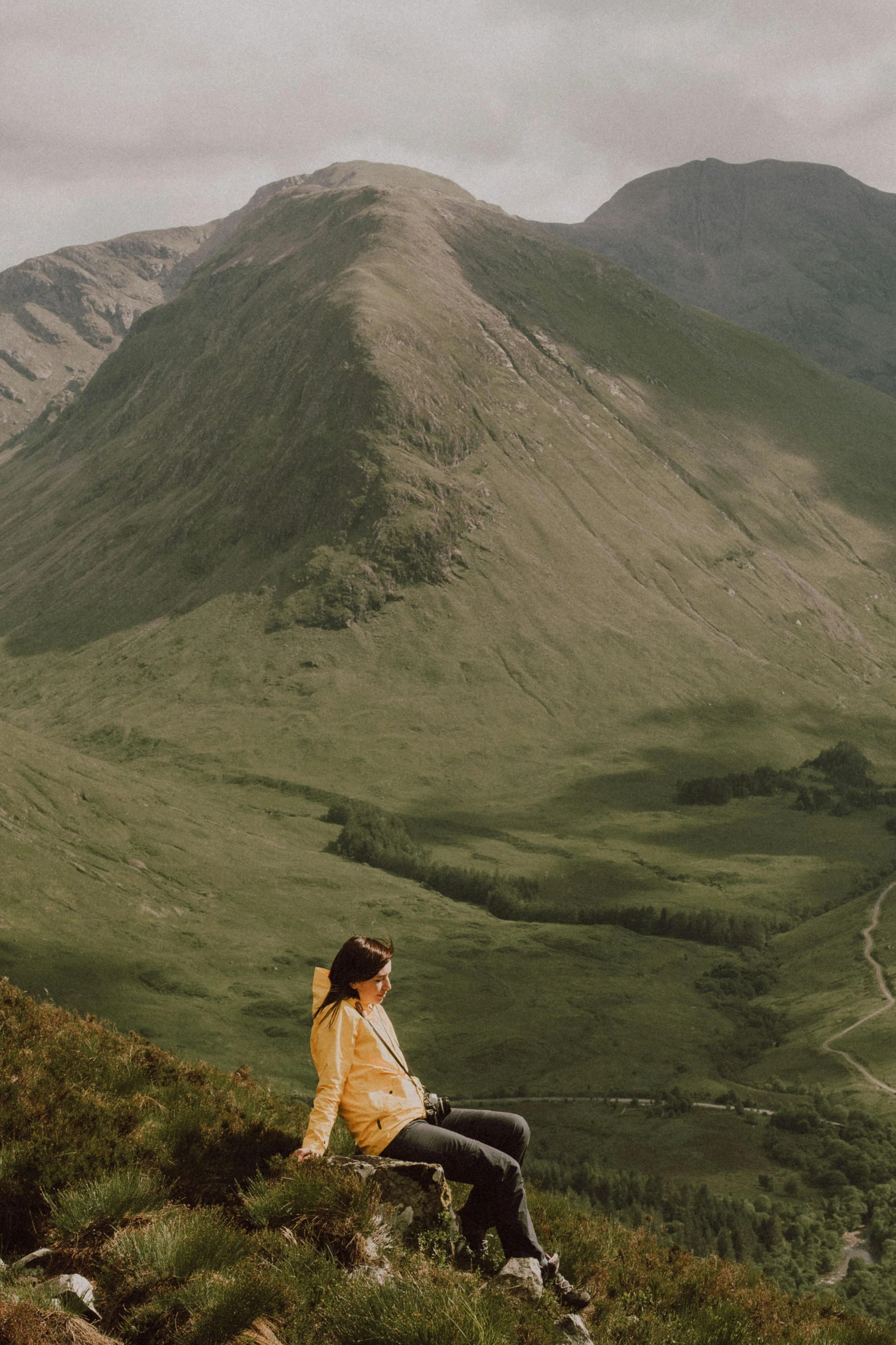 woman sitting on rock in alpine setting looking at mountains