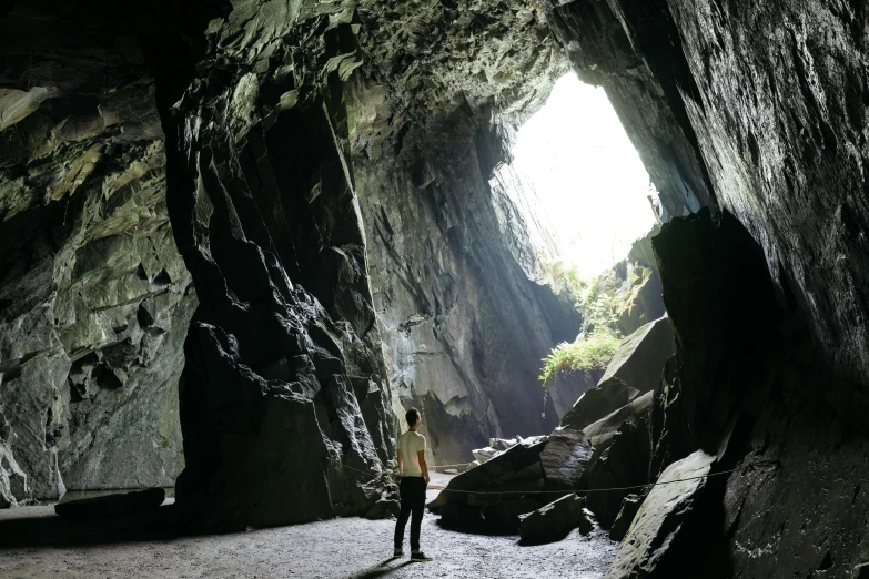 a woman standing in a cave on the side of a mountain