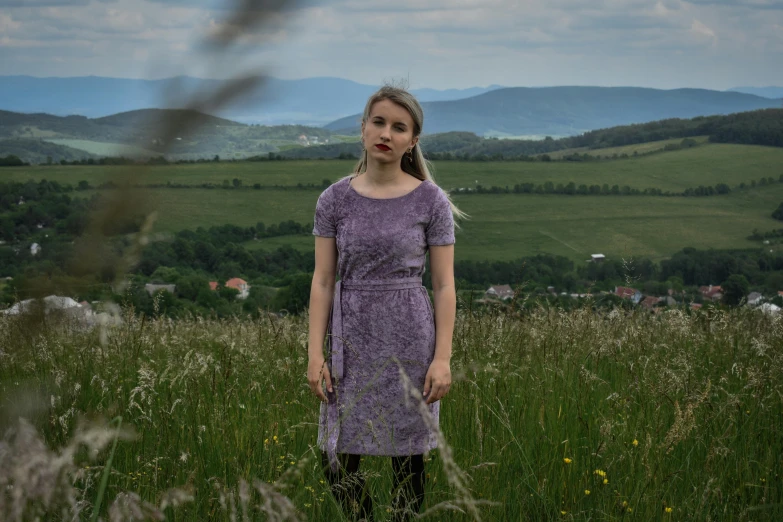 a girl wearing a purple dress standing in a field