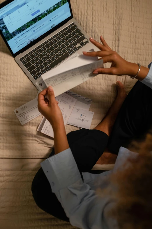 a woman sits on a bed and holds onto her laptop