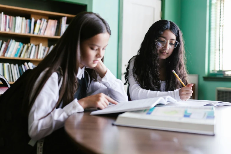 two girls in liry writing with notebooks on desk