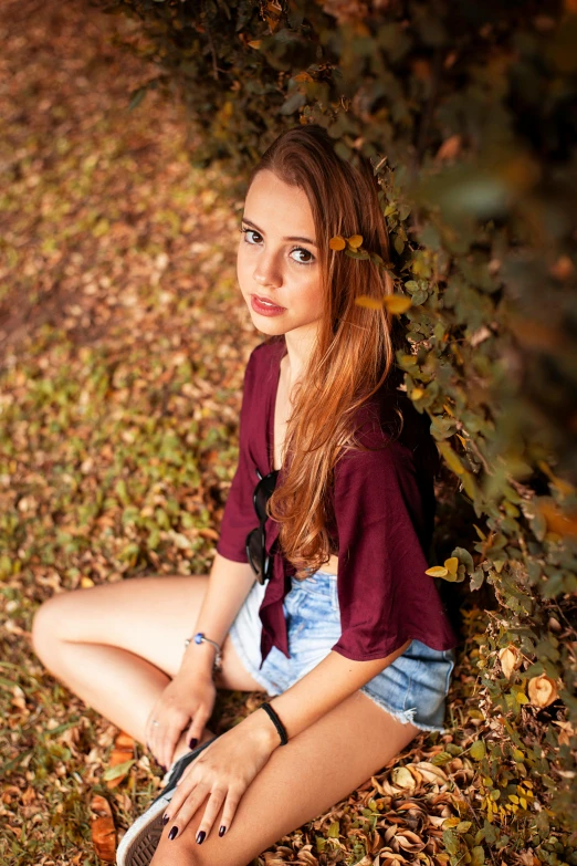 a woman sits on leaves in the grass