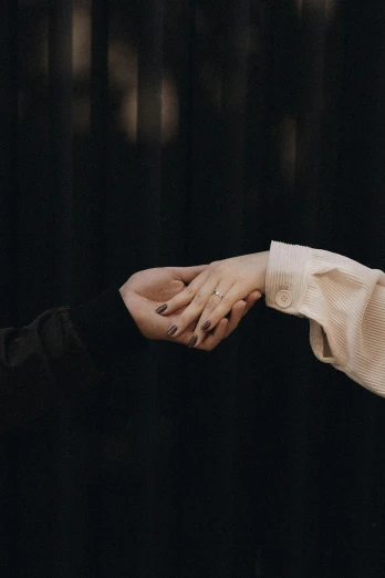 an older couple holds out their hand in a dark room