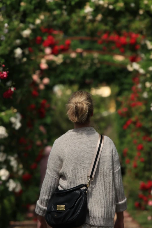 woman with large purse walking down path in garden