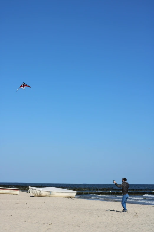 a man standing on the beach flying a kite