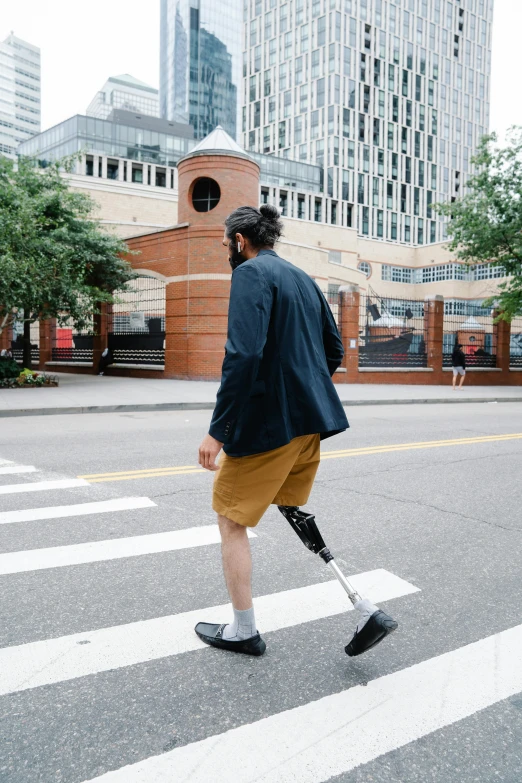 a man in a suit walking across a street while carrying an electric scooter