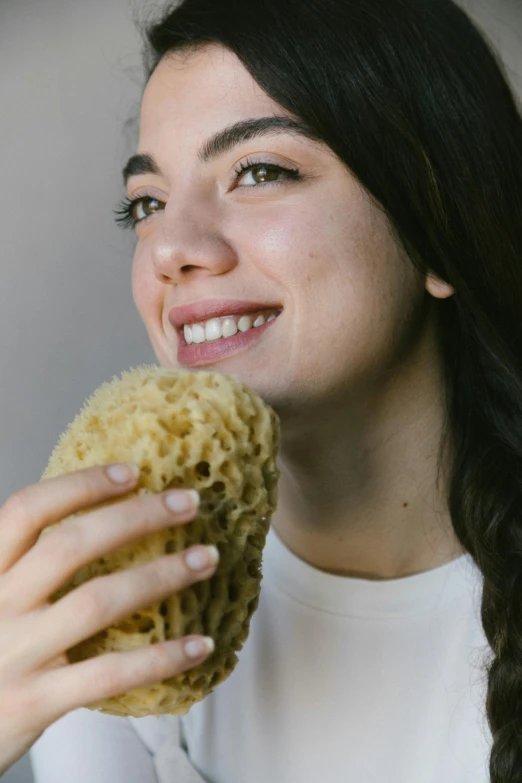 a smiling woman eating a sponge covered donut