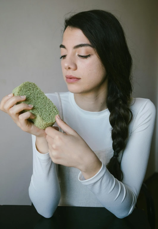 a woman sitting at a table with her hands wrapped around a broccoli floret