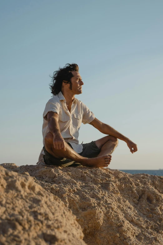 a man is sitting on top of a rock