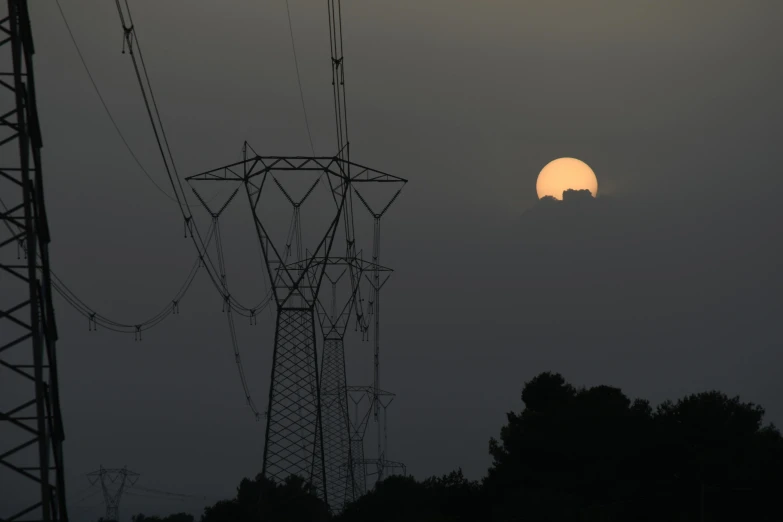 an image of a sun rising over power lines