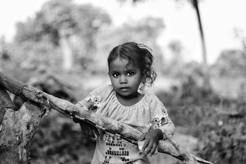 a small child standing by some logs on the ground