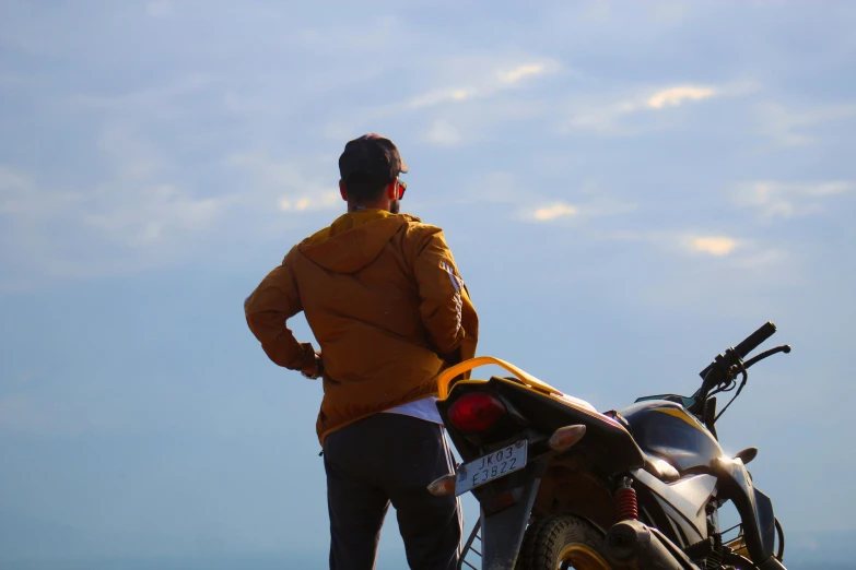 a man standing on a beach next to a motorcycle