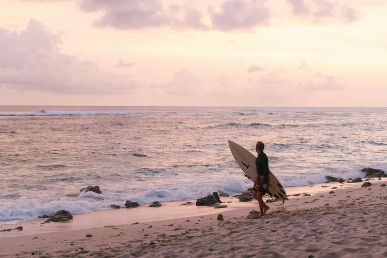 a surfer is carrying his board along the beach