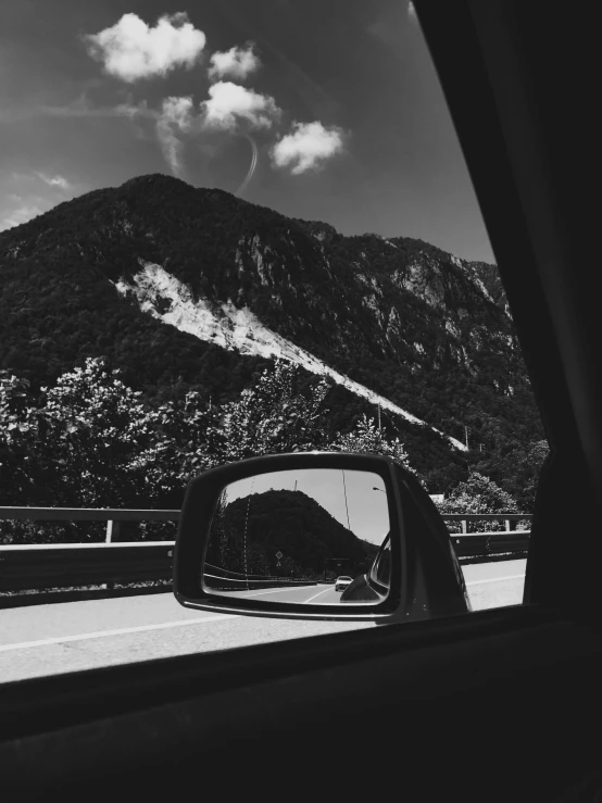 a car mirror on the side of a highway near a mountain