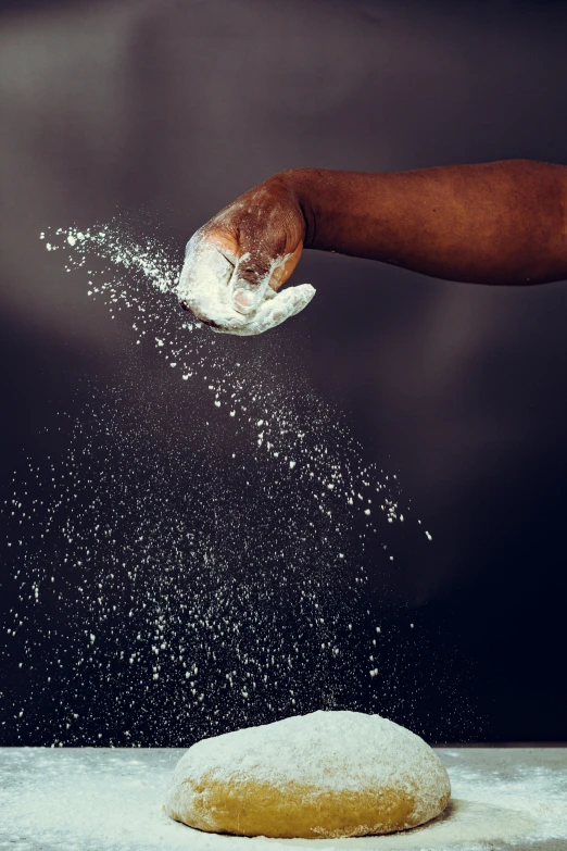 a person grabbing an uncooked doughnut from the ground