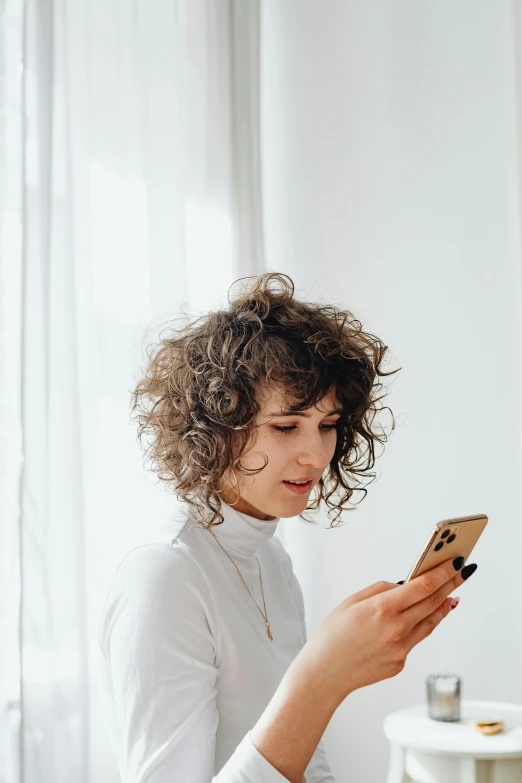 a woman standing in a room holding a cell phone