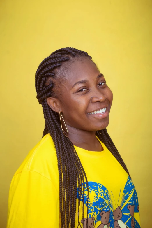 a woman with yellow shirt posing in front of a yellow wall