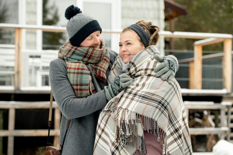 the man is putting his hat on the woman who is holding her scarf