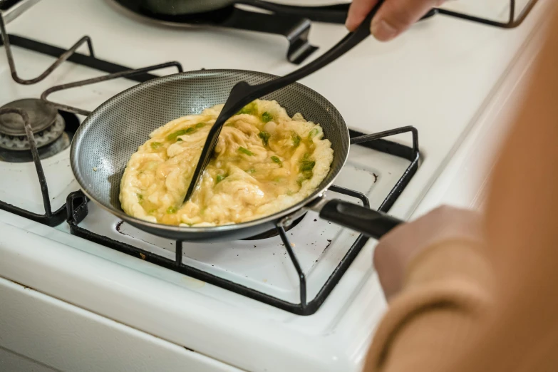 some people sitting around a pan on the stove