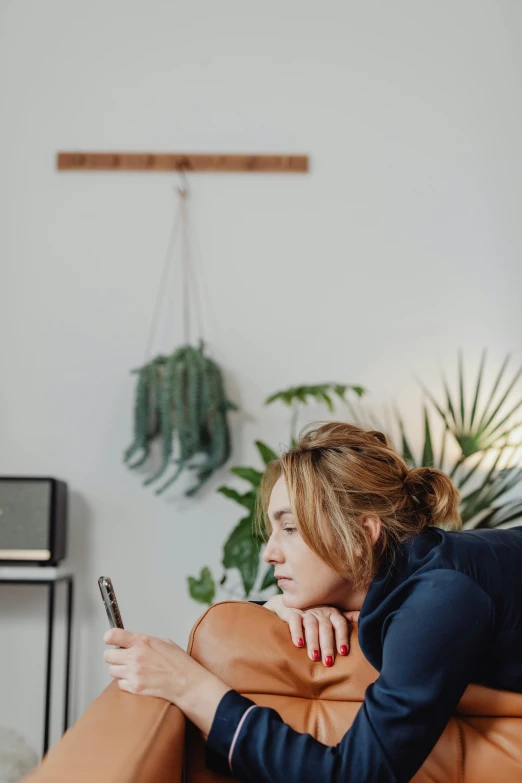 a woman leaning against a couch and holding onto a cellphone