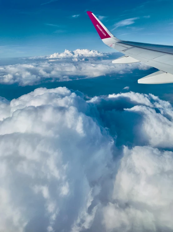 airplane wing and clouds below the blue sky