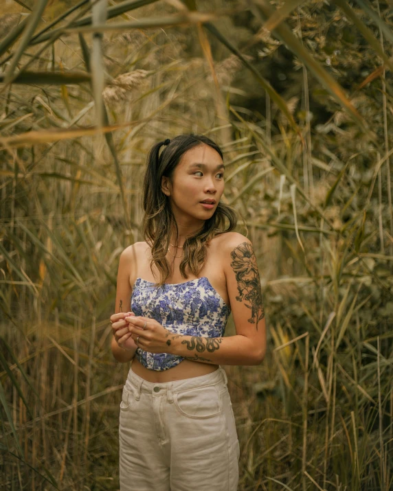 an asian woman stands in a field and looks at the camera