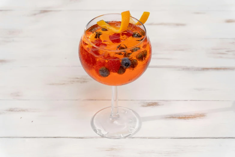 an orange and blueberry mulled in a wine glass with ice cubes