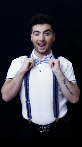a man wearing a white shirt, blue and white bow tie, suspenders, and a t - shirt