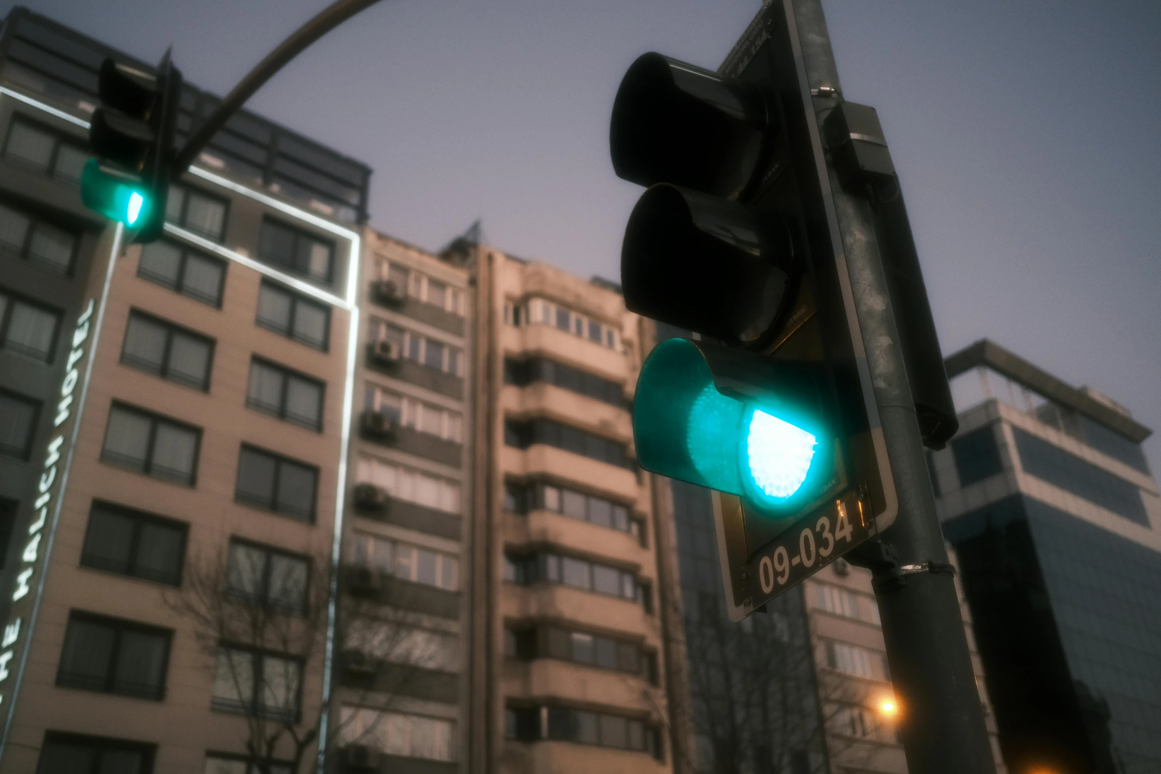 a traffic light with green light and buildings in the background