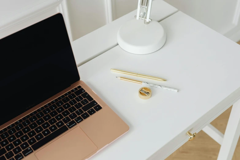 white desk with laptop and gold pen on it