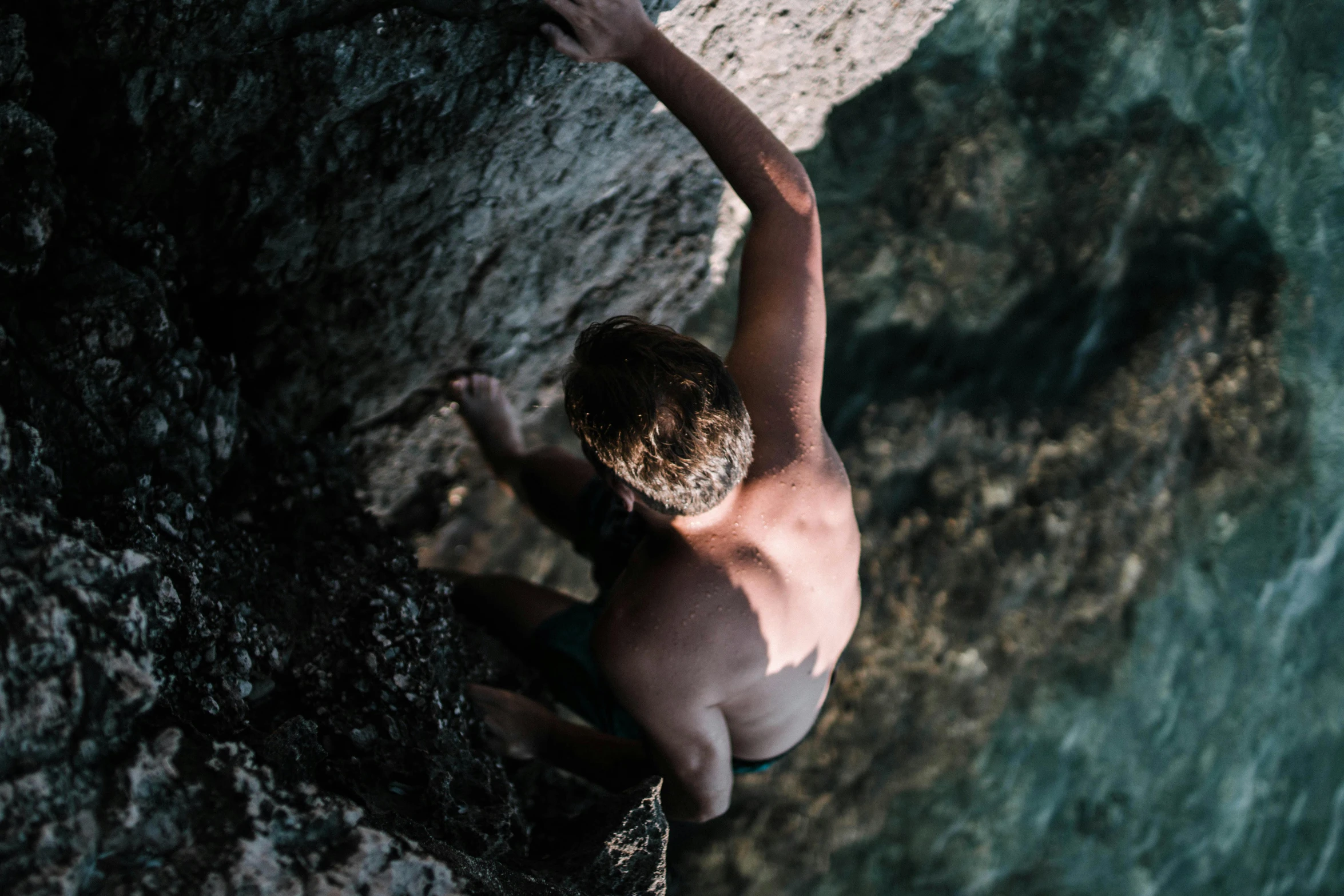 a person climbing a cliff above a body of water