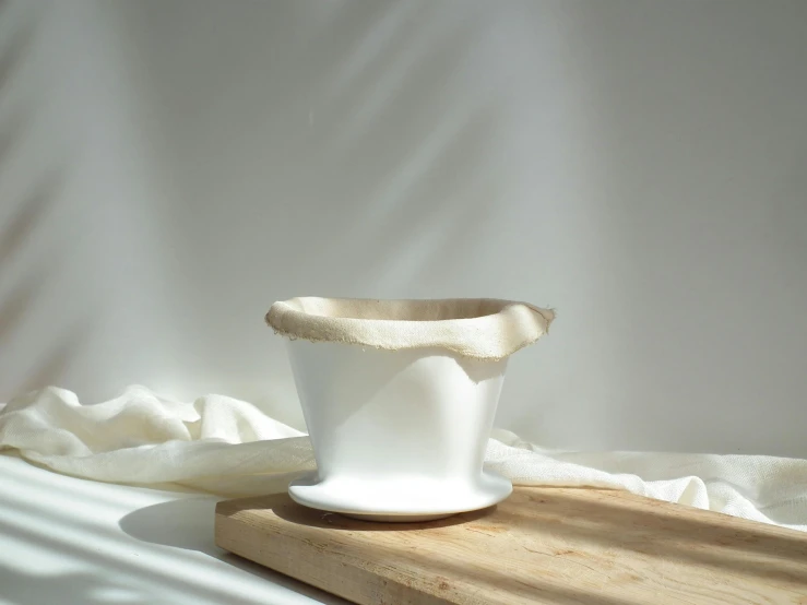 a white ceramic container sitting on top of a wood block