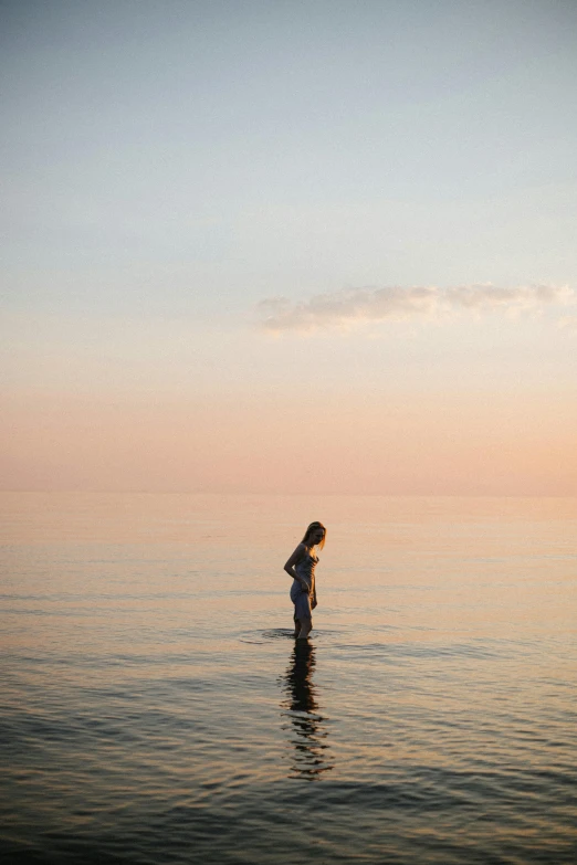 a woman is standing in the water near the shore