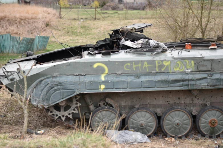 an old, abandoned tank is lying on the grass