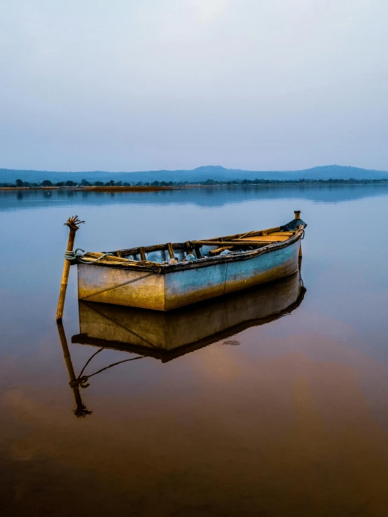 a wooden row boat floating on top of a lake