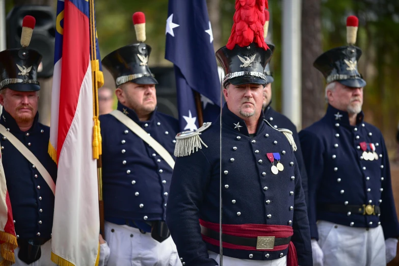 several men in military uniforms standing by flags